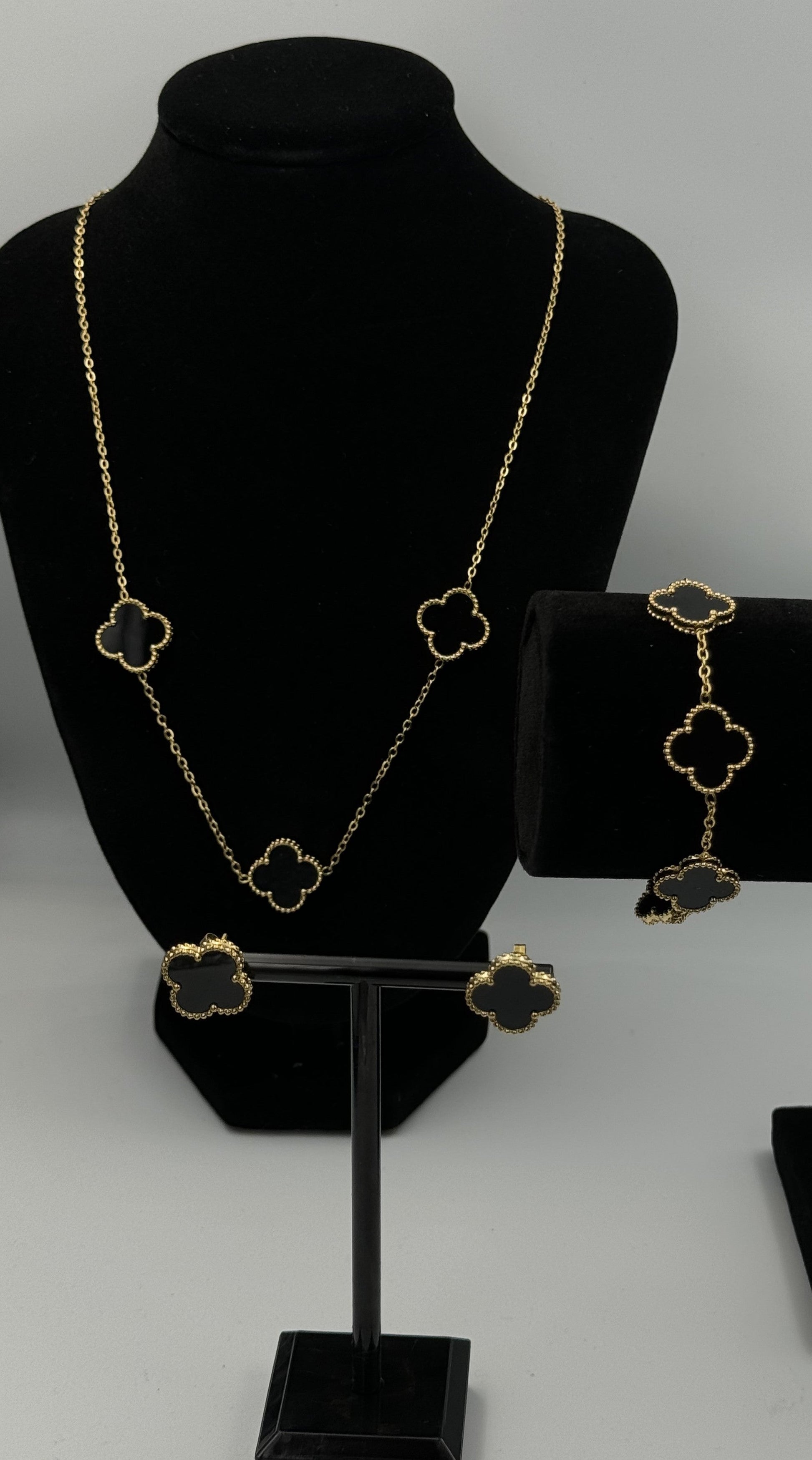 Mizori Jewelry black and gold stainless steel clover jewelry set on stand, including necklace, earrings, and bracelet, elegant minimalist design