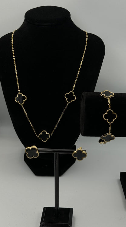 Mizori Jewelry black and gold stainless steel clover jewelry set on stand, including necklace, earrings, and bracelet, elegant minimalist design