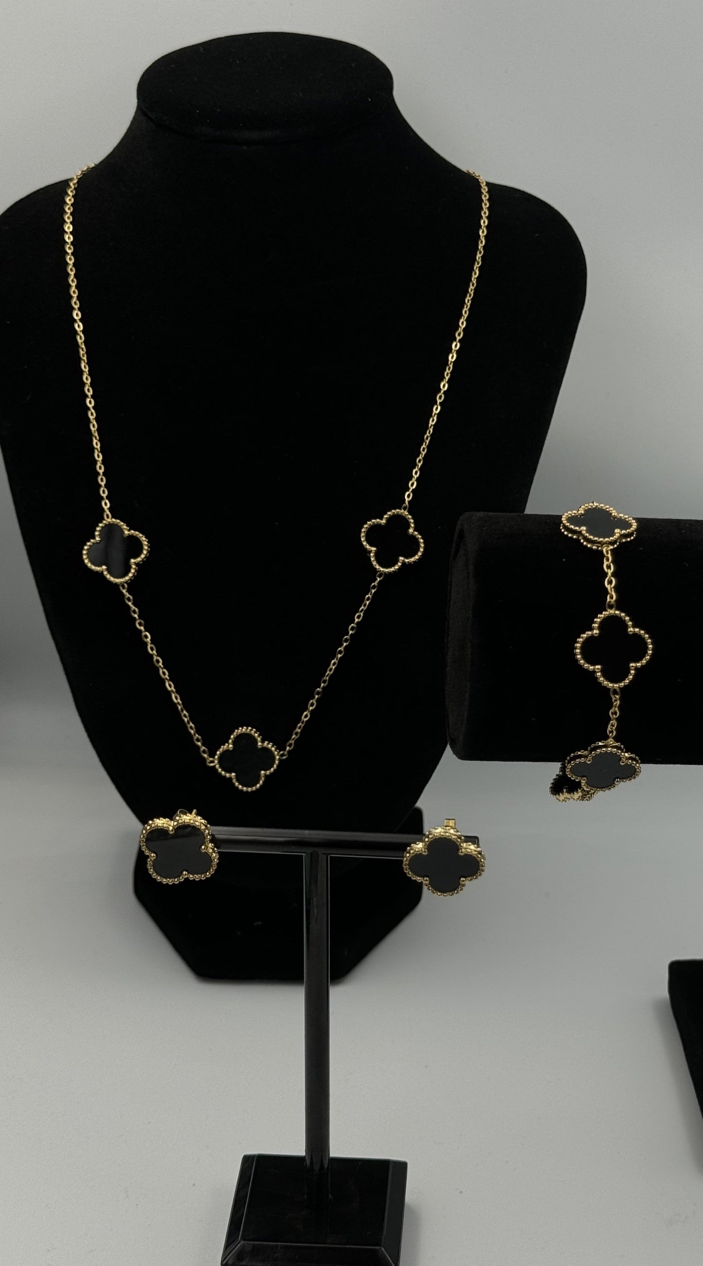 Mizori Jewelry black and gold stainless steel clover earrings displayed on a jewelry stand, elegant minimalist design, women’s fashion accessory.