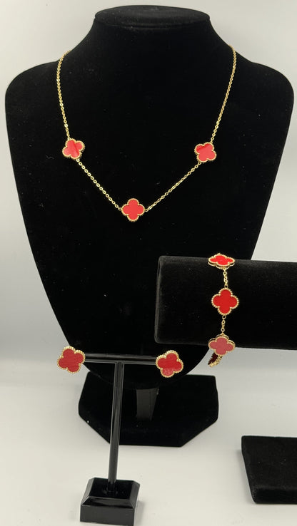 Mizori Jewelry red and gold stainless steel clover jewelry set on stand, including bracelet, necklace, and earrings, elegant minimalist design.